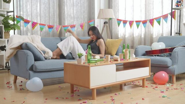 Drunk Asian Woman Wakes Up After Sleeping On A Sofa And Holding Her Head With Hands Due To Having A Headache In The Party Room At Home
