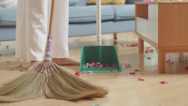 A Broom Being Used By Woman To Sweep The Floor After Drinking Alcohol For Celebrating Party At Home
