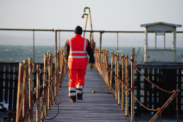 back worker walking on old pier