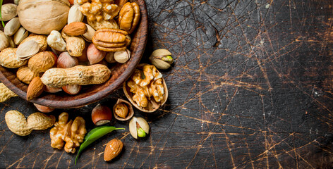 Different kinds of nuts in bowl with leaves.