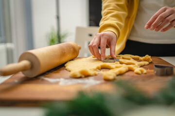 Top and side view of mother and daughter preparing gingerbread cookies with rolling pin in their kitchen in different shapes heart and stars 