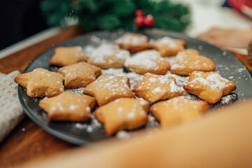 Top and side view of mother and daughter preparing gingerbread cookies with rolling pin in their kitchen in different shapes heart and stars 
