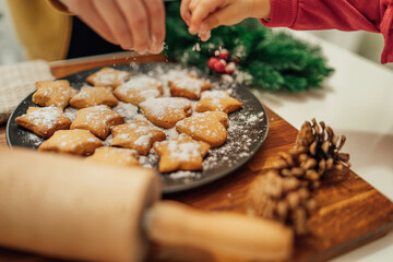 Top and side view of mother and daughter preparing gingerbread cookies with rolling pin in their kitchen in different shapes heart and stars 