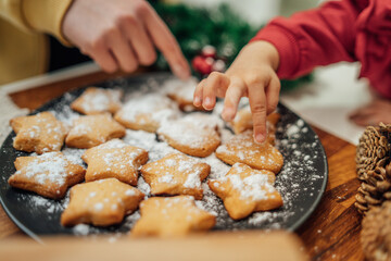 Top and side view of mother and daughter preparing gingerbread cookies with rolling pin in their kitchen in different shapes heart and stars 