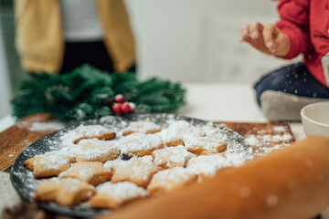 Top and side view of mother and daughter preparing gingerbread cookies with rolling pin in their kitchen in different shapes heart and stars 