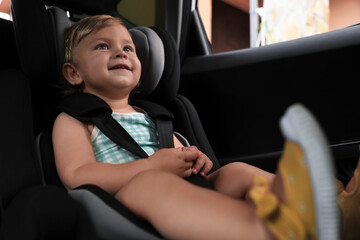 Obraz na płótnie Canvas Cute little girl sitting in child safety seat inside car