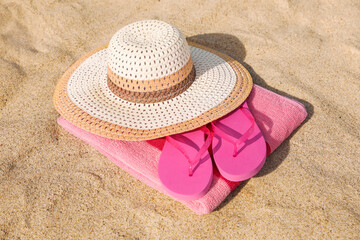 Fototapeta na wymiar Beach towel with straw hat and slippers on sand