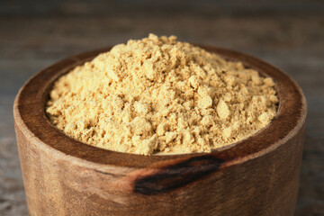 Bowl of mustard powder on wooden table, closeup