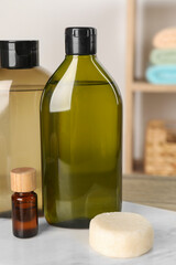 Solid shampoo bar and bottles of cosmetic product on wooden table in bathroom, closeup