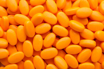 Tasty orange dragee candies as background, top view