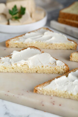 Delicious toasts with tofu cream cheese on white marble table, closeup
