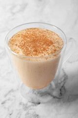 Glass cup of delicious eggnog on white marble table