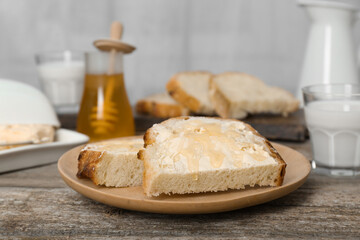 Slices of bread with butter, honey and milk on wooden table