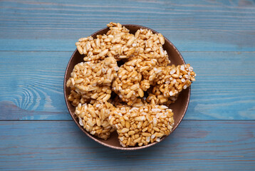 Bowl of puffed rice bars (kozinaki) on light blue wooden table, top view