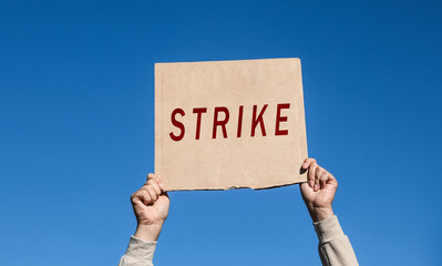 Young woman holding Strike sign against blue sky, closeup