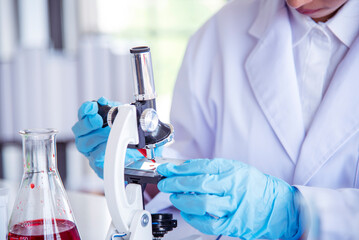 Asian Woman scientist hand write note research in medical lab look at science microscope medical...