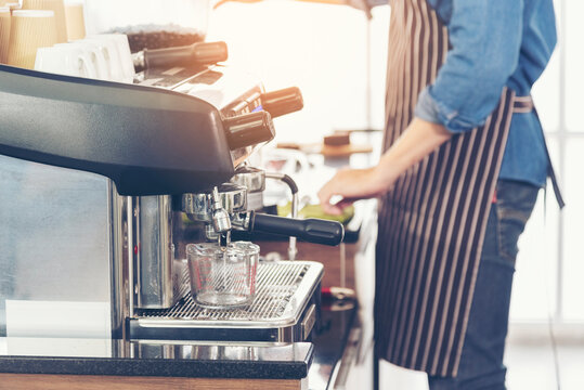 Close Up Hands Coffee Barista Man Make Hot Cup Espresso Shot From Coffee Machine. Cappuccino With Milk In Italian Coffee Shop Cafe. Close Up Hands Of Barista Use Machine Make Black Drinking Hot Cup