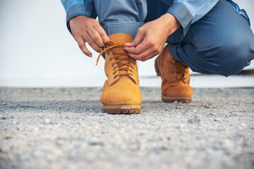 Man kneels down rope tie shoes industry boots for worker. Close up shot of man hands tied...