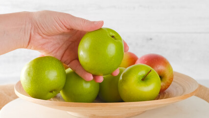 Woman hand holding an apple. Apples close-up on a wooden plate