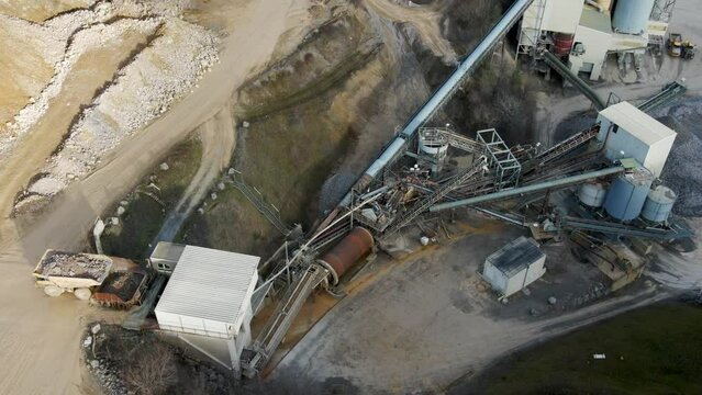At a German limestone quarry and lime processing plant, a rock truck dumbs into the feeder of a conveyor system