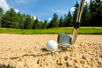 Golf ball in the sand, putter on a background.