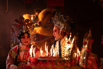 Male and female Chinese opera actors Light a candle to pray homage to the gods to enhance the...