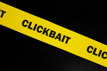 Clickbait scam alert, caution and warning concept. Yellow barricade tape with word clickbait in...