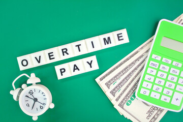 paper money, a calculator and a bell with the word overtime pay. overtime concept. the concept of...