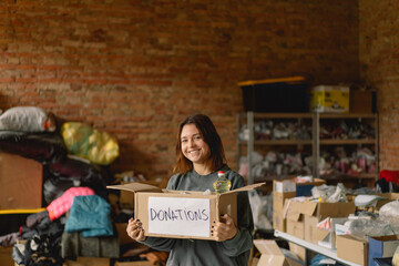 Volunteer teengirl preparing donation boxes for people. Donation clothing for refugees, support of war victims. Humanitarian aid concept.Helping people