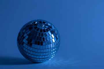 Disco ball on a blurred blue background, the concept of dancing, disco, music and parties, copy space.