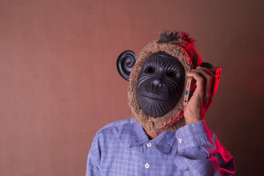 Front view photo of man in black monkey mask calling isolated on brown background