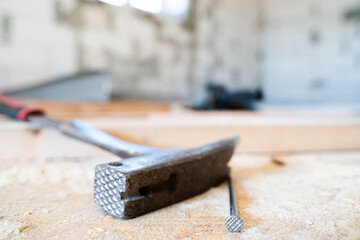 Roofing hammer with a nail close-up on a wooden surface on a blurred background