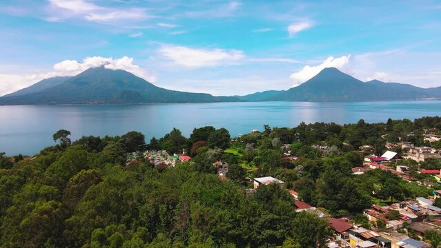 Aerial Flyover Village Toward Lake and Volcanoes - Lake Atitlan, Panajachel, Guatemala