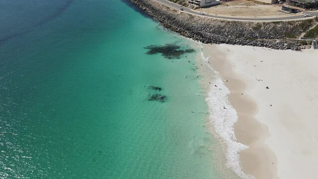 Drone footage of Mindarie Beach showing off the clear ocean water and white sands of Perth Western Australia. Flying towards the road and people playing and swimming in the ocean