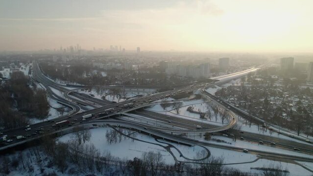 Establishment footage of the snow covered city of Warsaw, Poland. Traffic in the intersection S8 at rush hour with the cityscape in the background.