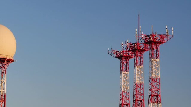 Slowly panning from a radar dome to reveal the antennas and airport control tower