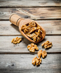 Peeled walnut in a wooden scoop .