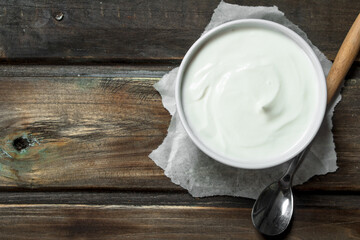 Fresh sour cream in bowl with spoon .