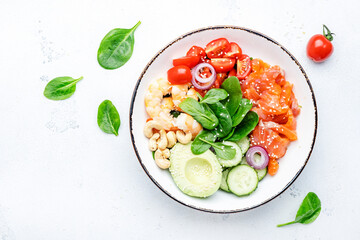 Salmon salad for ketogenic diet with shrimp, avocado, spinach, cucumber, tomato, cashew nuts, sesame. Low-carbohydrate breakfast rich in healthy fats. White table background, top view