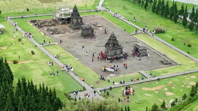 Ancient stone temple surrounded by green meadows, aerial orbit view