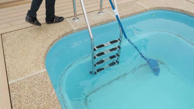 Man cleans the pool with a portable vacuum cleaner. Preparing and cleaning the pool for the swimming area
