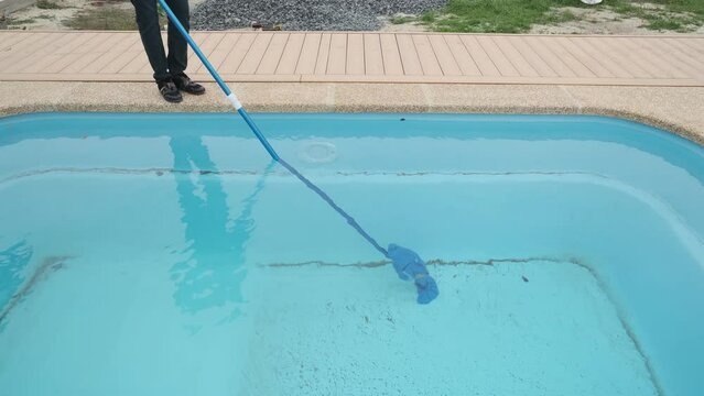Man cleans the pool with a portable vacuum cleaner. Preparing and cleaning the pool for the swimming area
