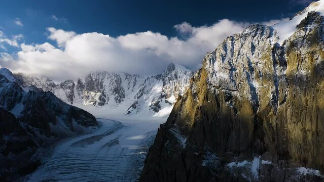 Epic cinematic aerial drone shot of a large passage and mountain atop the Ak-Sai glacier during the sunset in Kyrgyzstan