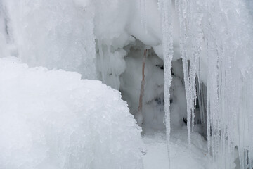 Icicles hang next to the niche. Frozen entrance to an animal burrow. The winter freezing rain has passed.