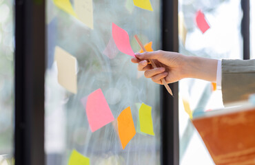 Business female employee with many conflicting priorities arranging sticky notes commenting and...