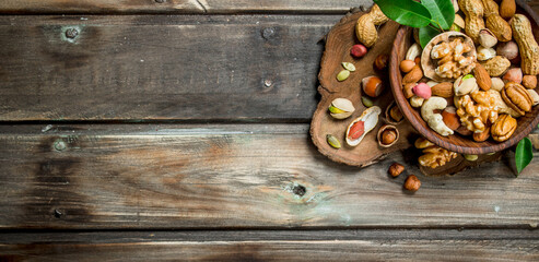 Different kinds of nuts in bowl with leaves.