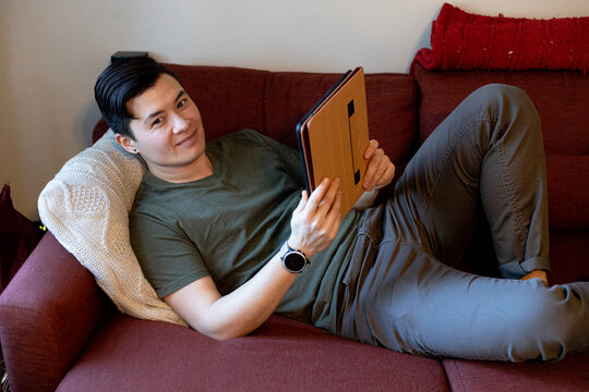Transgender man reading on a on sofa