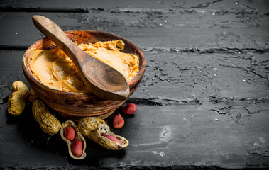 Peanut butter in bowl with wooden spoon .