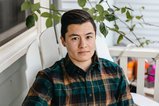 A transgender man sits on his porch