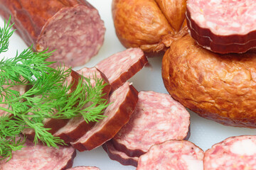 two types of sausages on a white cutting board with a sprig of dill, macro